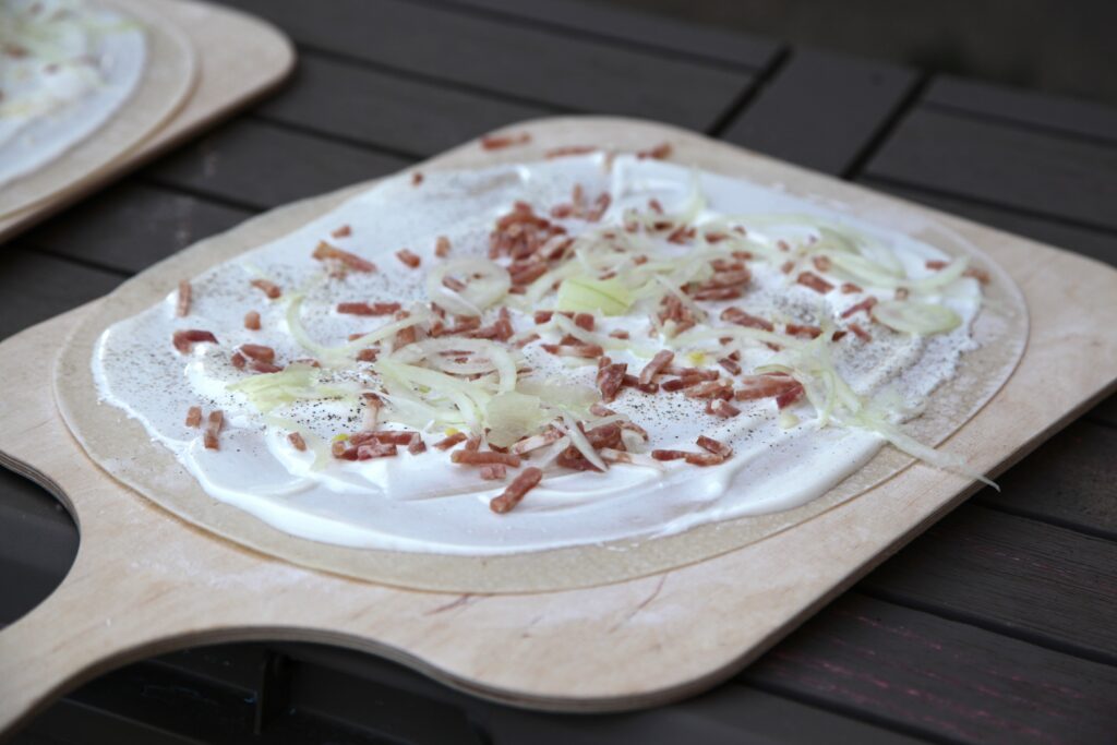 Original Elsässer Flammkuchen mit knusprigem Hefefreiem Teig, Crème fraîche, Speck und Zwiebeln – einfach selbst gemacht.